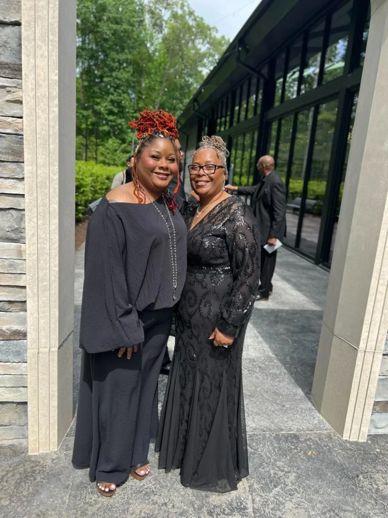 Two women standing together outdoors in dark outfits